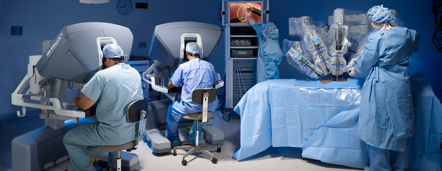 Cirurgiões operando com o sistema robótico da Vinci no centro cirúrgico